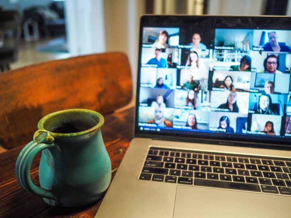 A laptop is open to a Zoom call with many people pictured