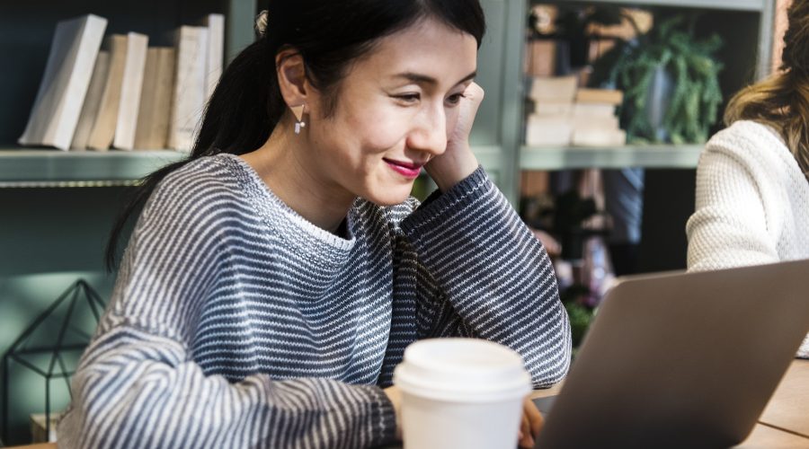 Access to Coaching Notes An asian woman sitting at a table with an open laptop computer