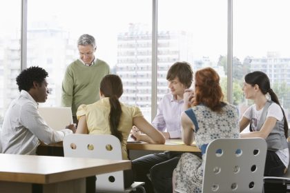 Group of business people, both men and woman sitting around a conference table and talking