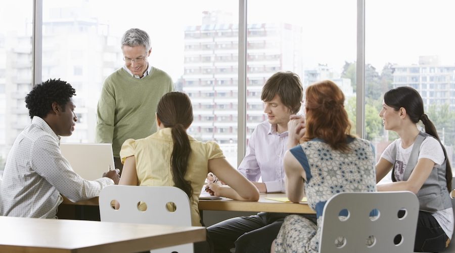 Group of business people, both men and woman sitting around a conference table and talking