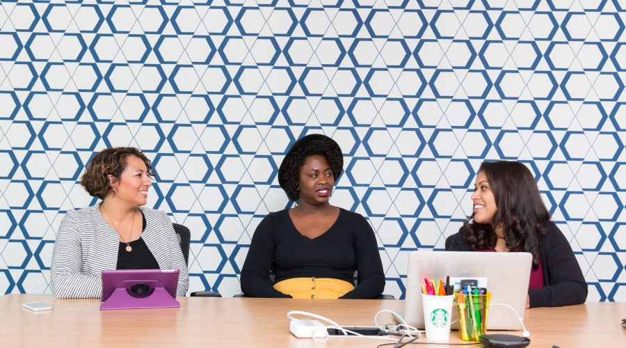 3 woman are sitting at a table and talking.