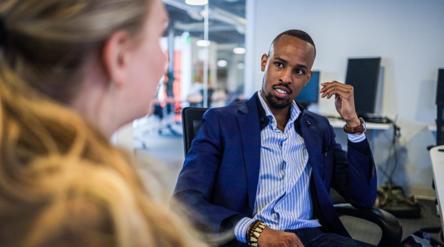 A white woman, and an African American man are sitting and talking