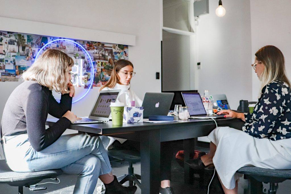 People sitting at a large table with laptop computers