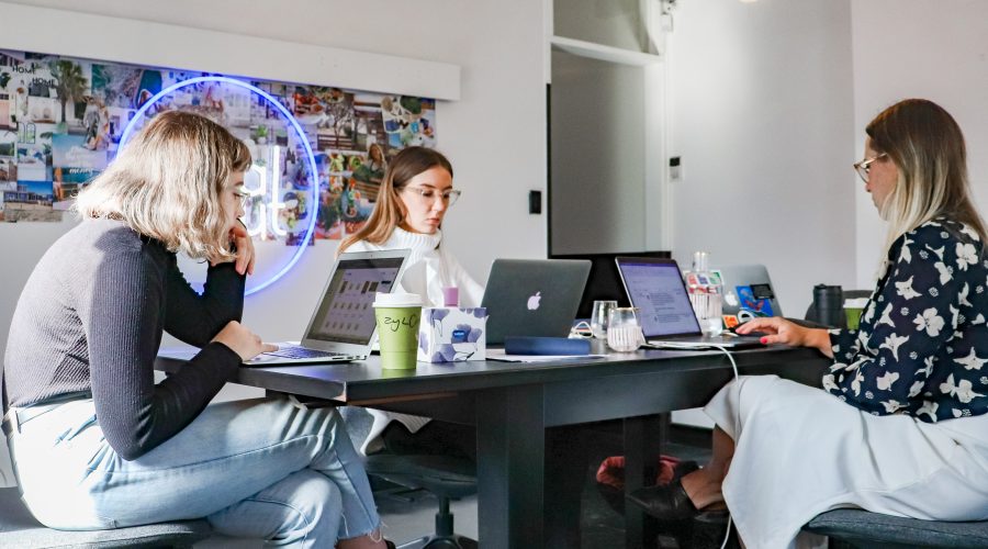 People sitting at a large table with laptop computers