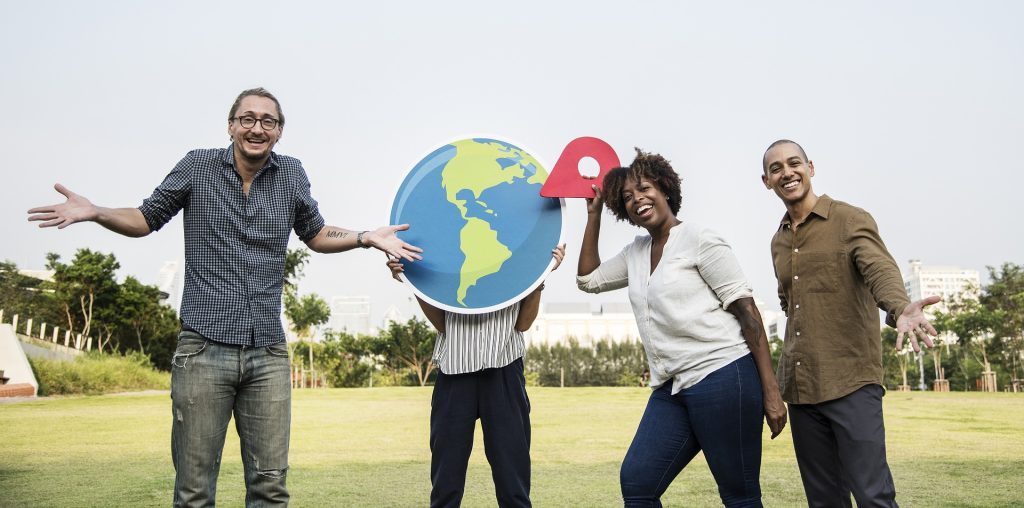 Group of multi-racial people staying outside, holding up a picture of the earth