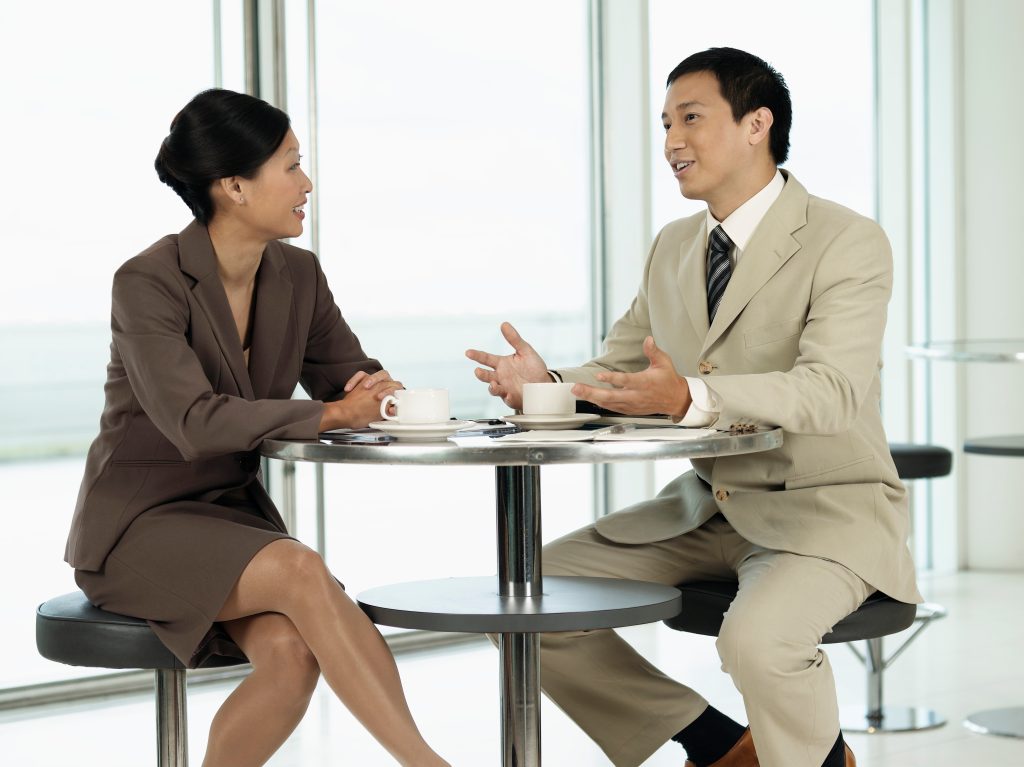 A woman and  man are sitting at a table talking. 