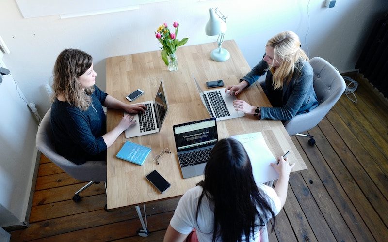 3 Woman are sitting around a table talking