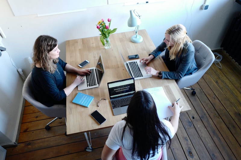 3 Woman are sitting around a table talking 