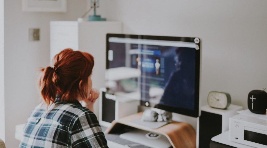 A woman is sitting infant of a desktop computer