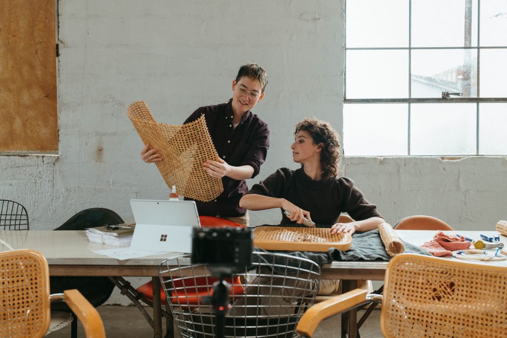 A man is standing holding a product in his hand while a women is sitting talking with him