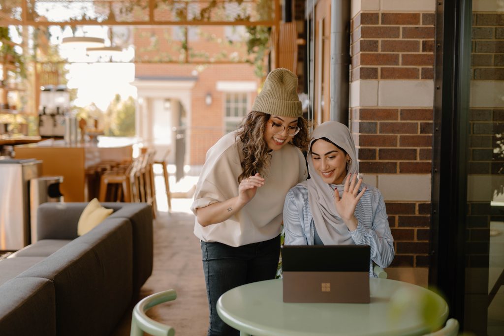 A woman sitting is talking to a woman leaning over her