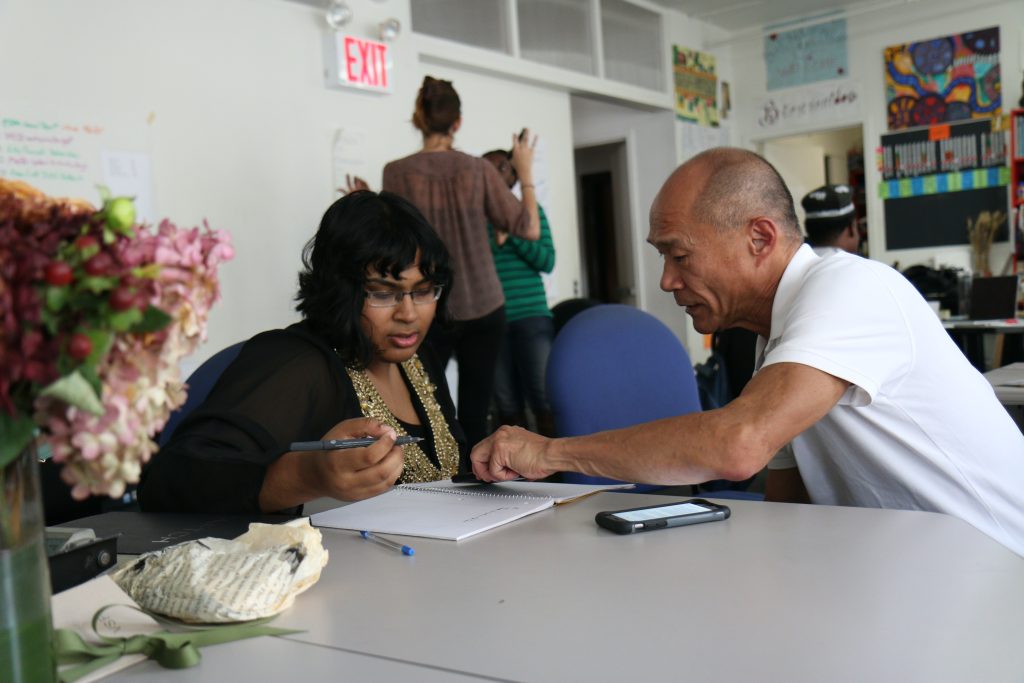 A white male is talking to an African America  woman.