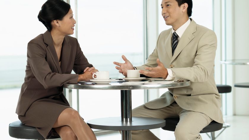 A man and a women, in business suits, are sitting and talking