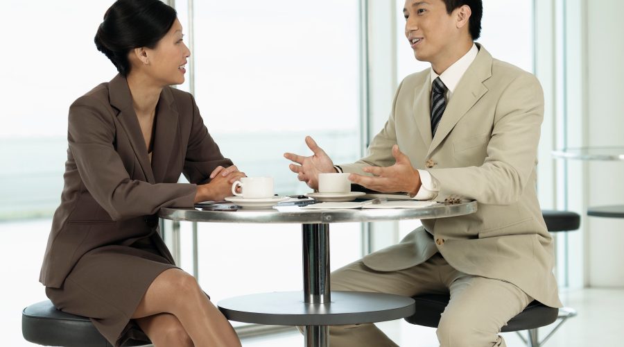 A man and a women, in business suits, are sitting and talking