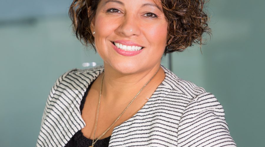 A woman in business attire is standing and smiling