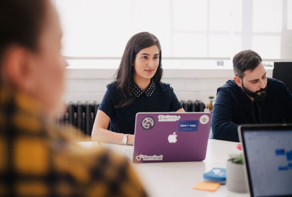 Woman in business attire sitting at a work table with laptops