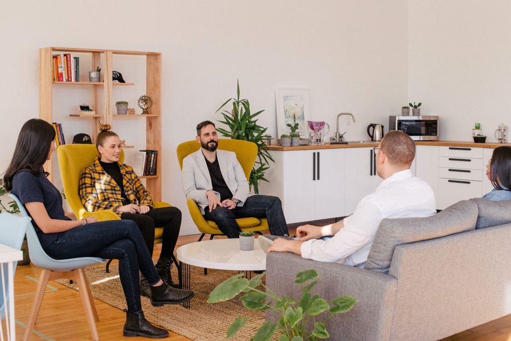 a woman and 2 men are sitting in a circle and talking