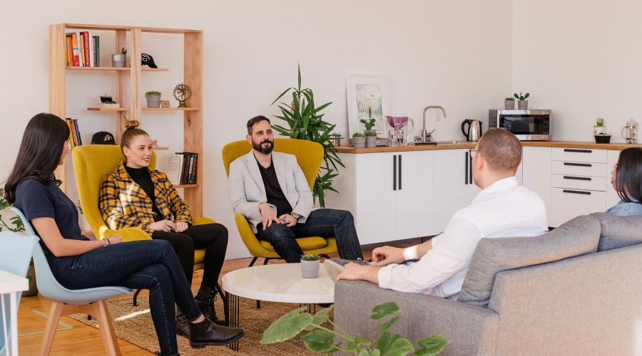 a woman and 2 men are sitting in a circle and talking