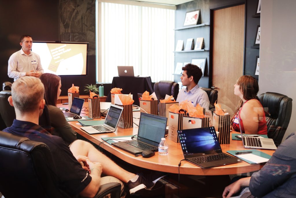 A group of business people, both men and woman are sitting at a conference table