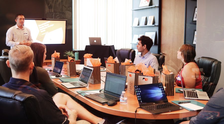 A group of business people, both men and woman are sitting at a conference table