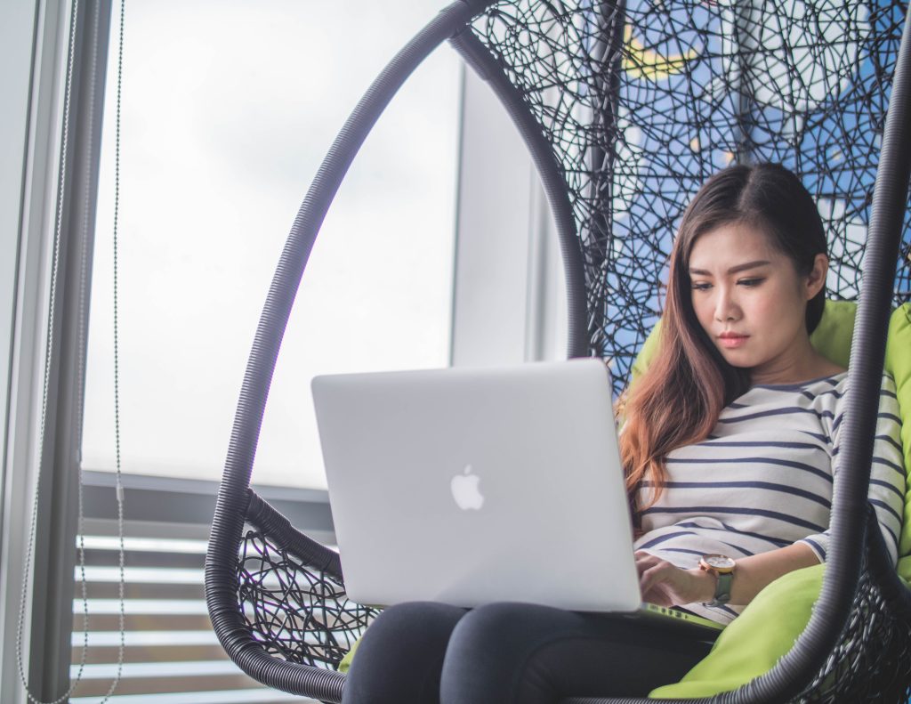 A girls is sitting g in a chair with a laptop computer