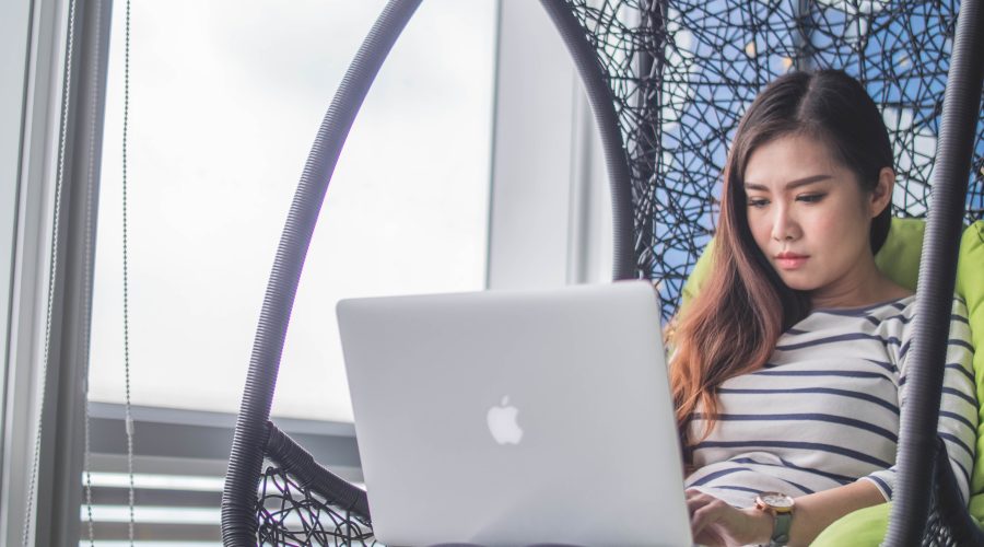 A girls is sitting g in a chair with a laptop computer