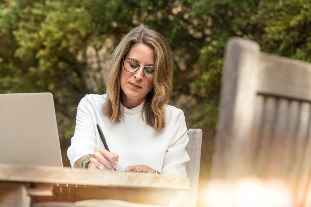 A woman is sitting writing in a book or journal