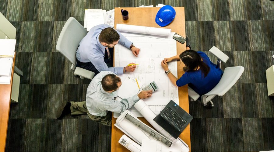 A group of people are sitting at a desk talking