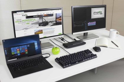 A desk with a computer, laptop computer, cell phone and microphone