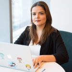 A woman is sitting at a table with her laptop computer open.