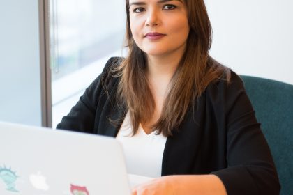A woman is sitting at a table with her laptop computer open.
