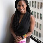 An African American woman is sitting with a book in her hand