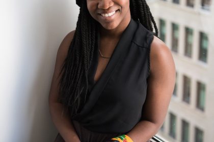 An African American woman is sitting with a book in her hand