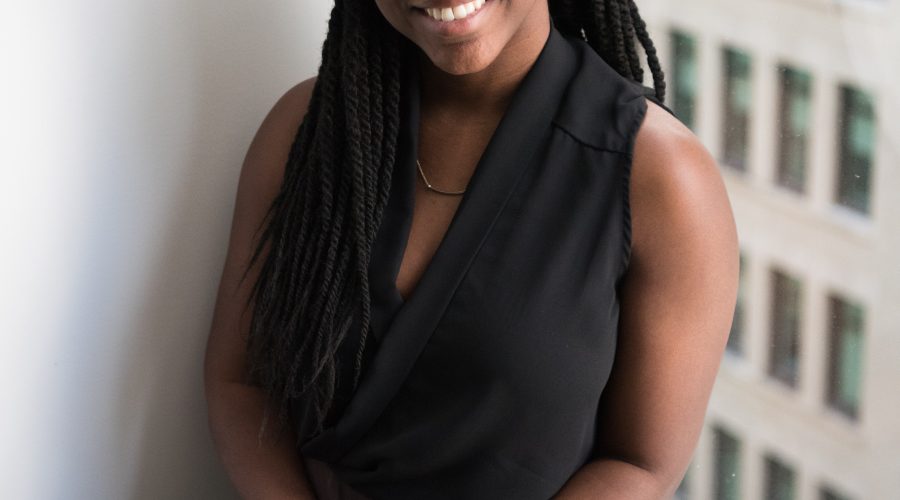An African American woman is sitting with a book in her hand