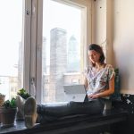 A woman is sitting typing on a laptop computer