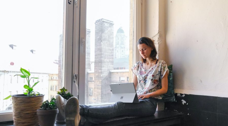A woman is sitting typing on a laptop computer