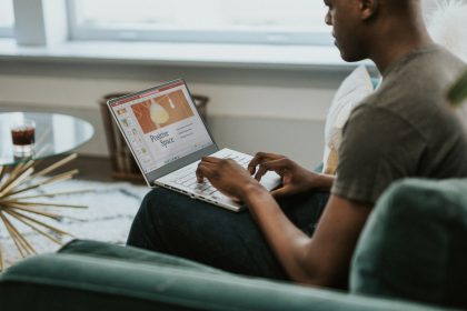 An African American man is sitting on his laptop