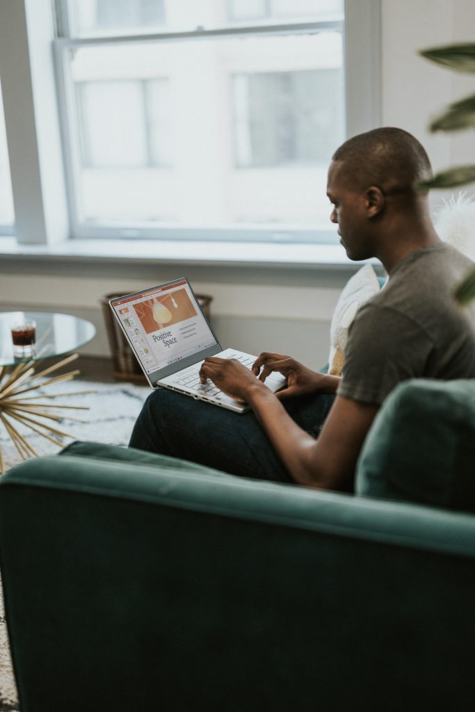 An African American man is sitting on his laptop