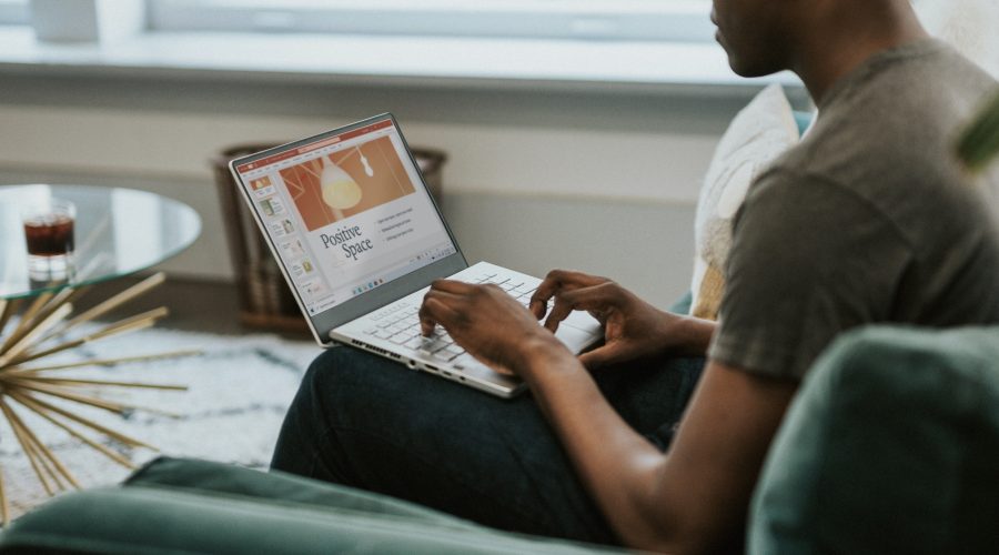 An African American man is sitting on his laptop