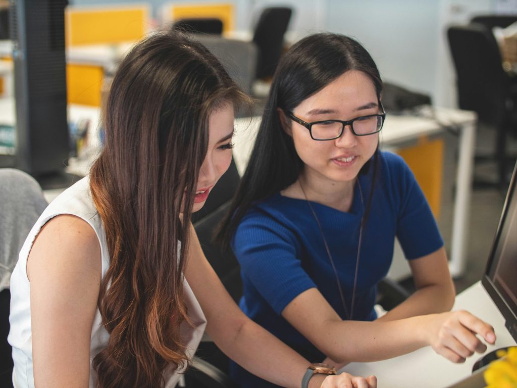 2 Girls are sitting at a desk and talking