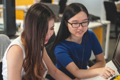 2 Girls are sitting at a desk and talking