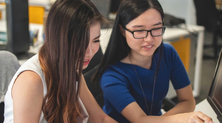 2 Girls are sitting at a desk and talking