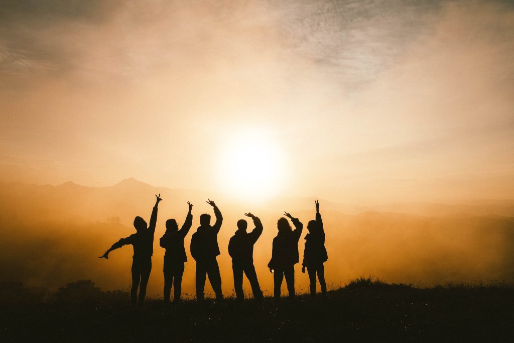 A group people are celebrating on top of a hill