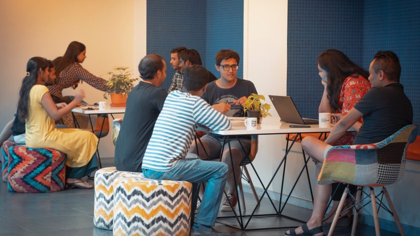 A group of men and woman are sitting and appear to be studying