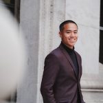 An African American man is standing and smiling