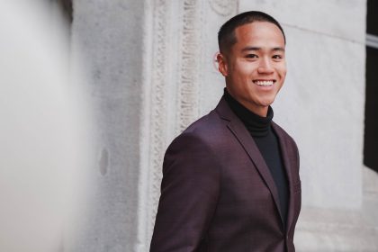 An African American man is standing and smiling