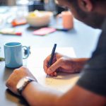 A man is sitting and writing