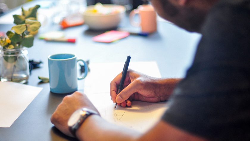 A man is sitting and writing