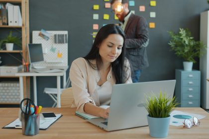 A woman is sitting at her computer laptop