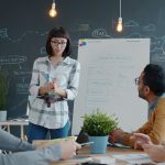 A group of men and woman are sitting in classroom or conference room and talking or training